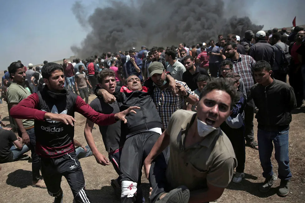 Palestinske demonstranter bærer en mann som ble skutt og såret. Foto: AP / NTB scanpix