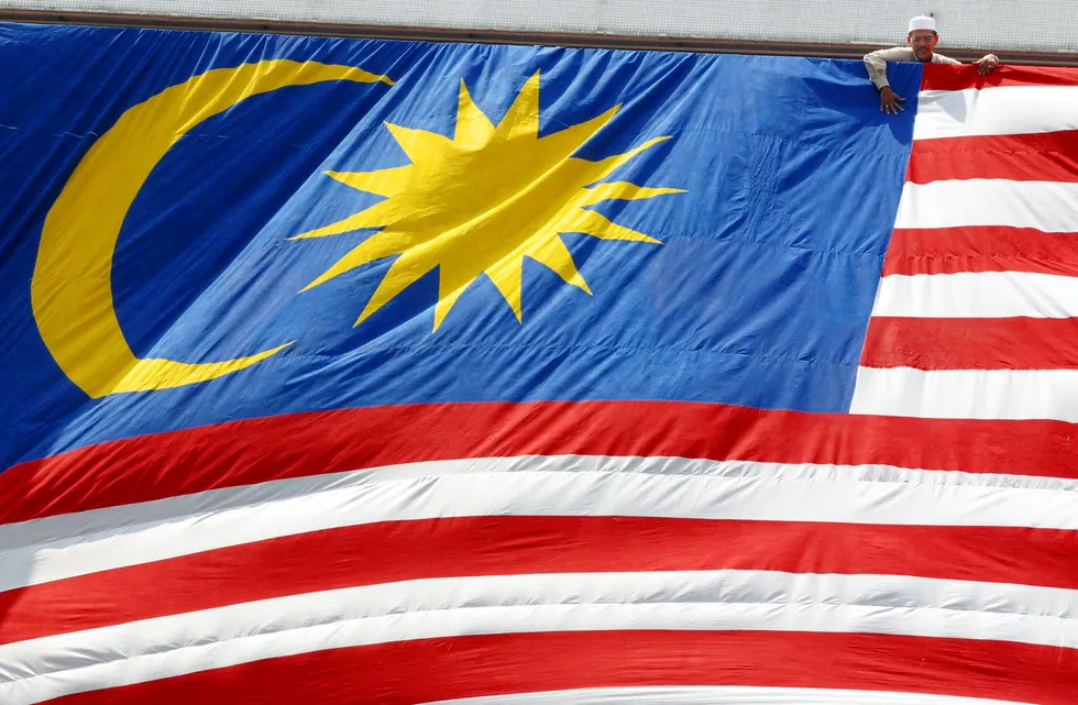 Patriotic: a worker adjusts a giant Malaysian National Flag at a building in the capital Kuala Lumpur.