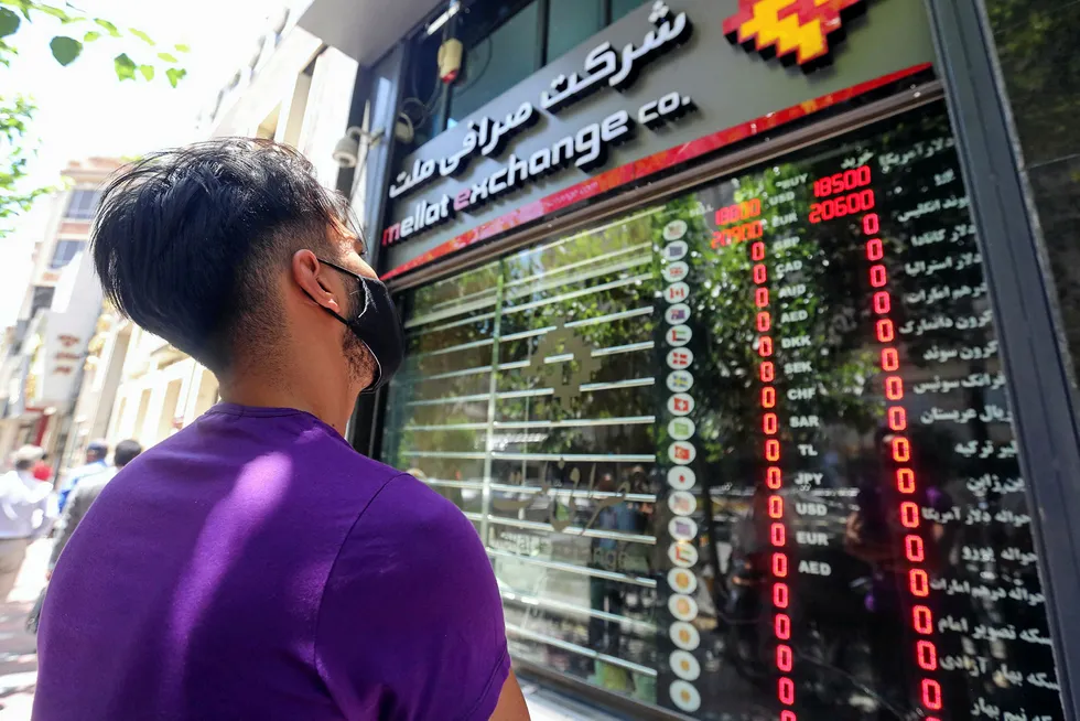 Rial trouble: an Iranian youth, wearing a protective mask due to the COVID-19 pandemic, checks the currency exchange rates in Tehran