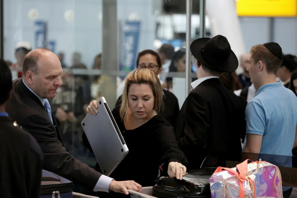 En reisende får laptopen kontrollert på JFK-flyplassen i New York tidligere i mai i år. Nå kan lignende utstyr ble forbudt på reise til og fra USA. Foto: Joe Penney/Reuters/NTB Scanpix