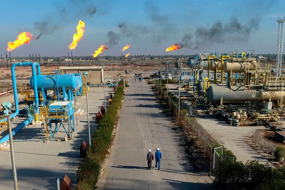 Det internasjonale energibyrået (IEA) nedjusterer prognosene for vekst i global oljeetterspørsel. På bildet ses arbeidere som går langs Nihran Bin Omar-feltet nær Basra i Irak.