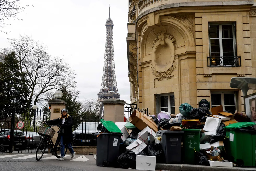 Piling up: A woman walks past garbage piled up since waste collectors went on strike against the French government's proposed pensions reform