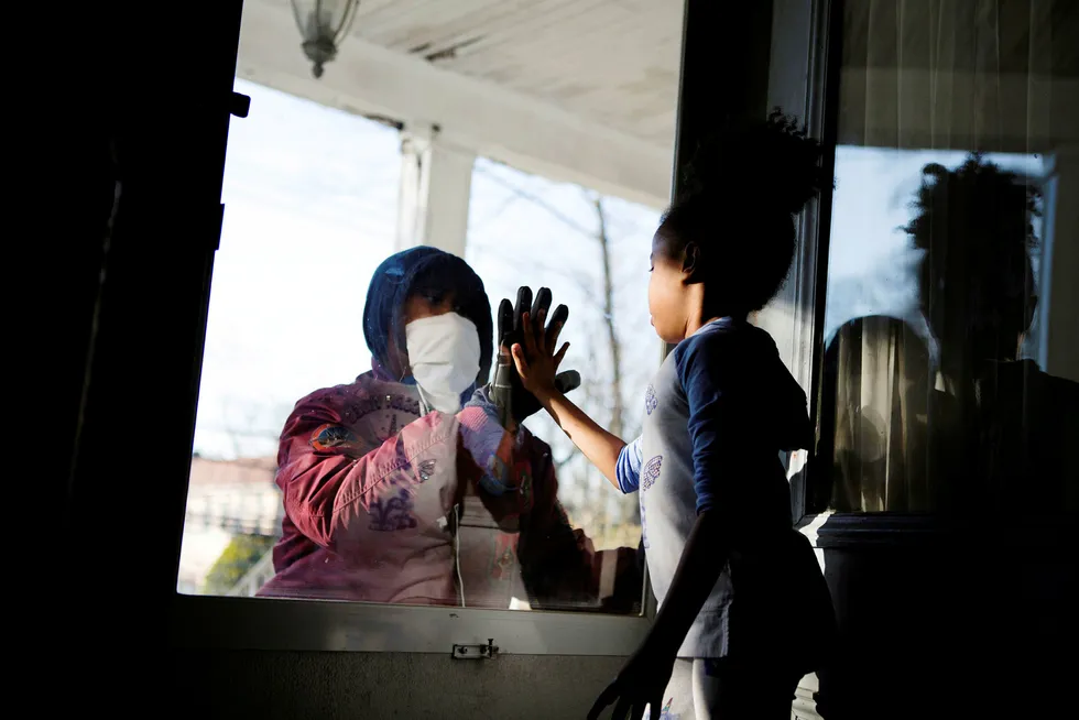 Sosial distanse preger verden under epidemien. Her hilser en helsearbeider på datteren sin gjennom en glassdør.