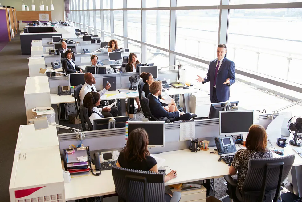 Young male manager addressing workers in open plan office --- Foto: IStockphoto/Getty Images