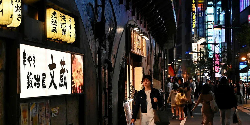 A woman walks at night in Yurakucho in Tokyo.