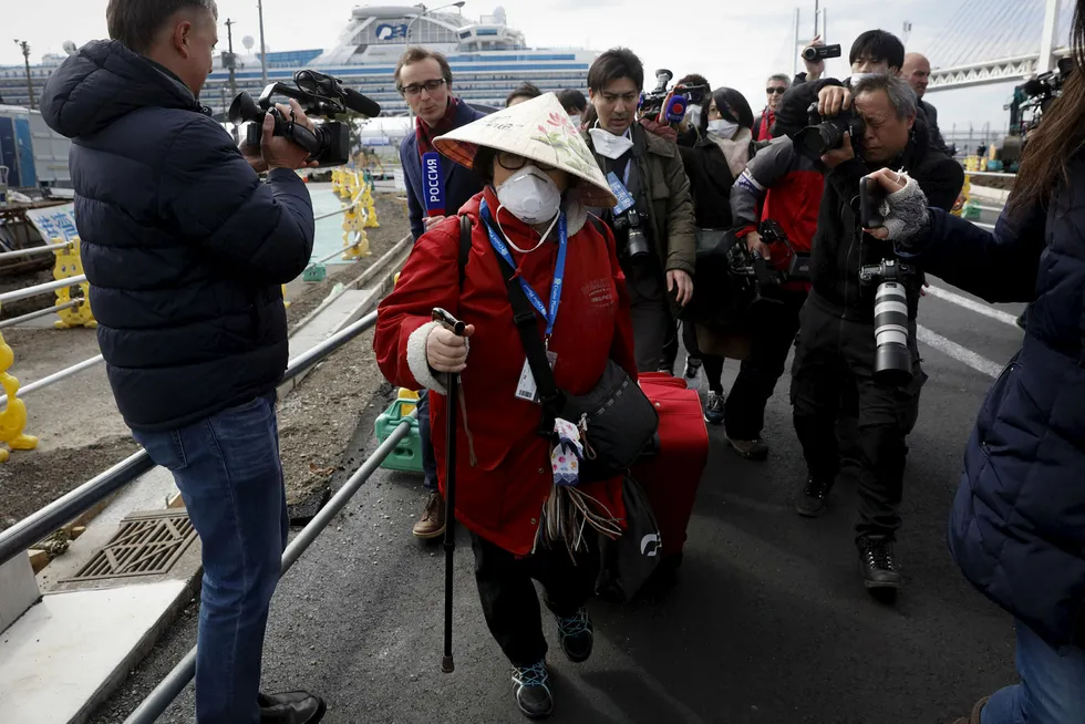 En passasjer er omgitt av media i det hun kommer i land fra det virusrammede cruiseskipet Diamond Princess som ligger til kai i Yokohama i Japan.