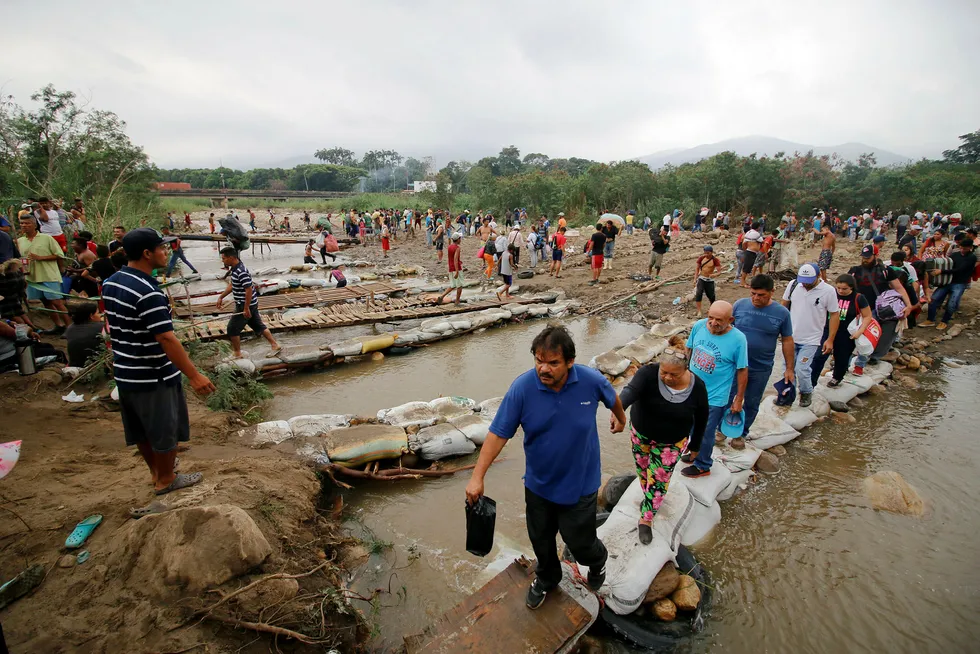 Folk fra Venezuela krysser elven Tachira og inn i Colombia.