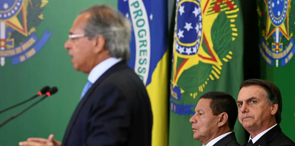 Brazilian President Jair Bolsonaro (R) and Vice-President Hamilton Mourao (C) listen to Finance Minister Paulo Guedes.