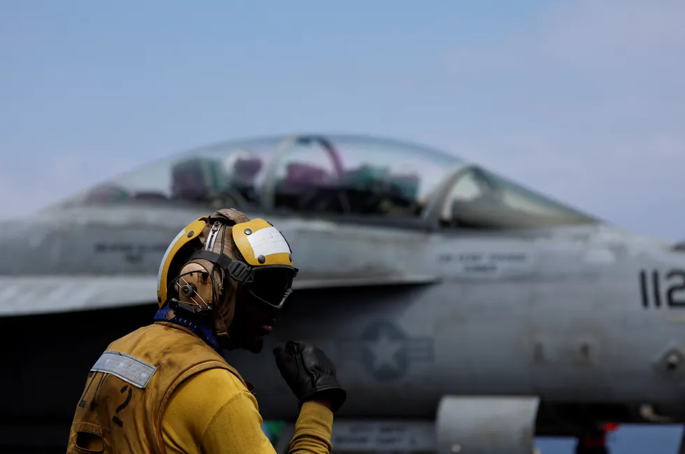 A flight officer communicates with his team on the flight deck of the USS Dwight D. Eisenhower aircraft carrier in the Red Sea.