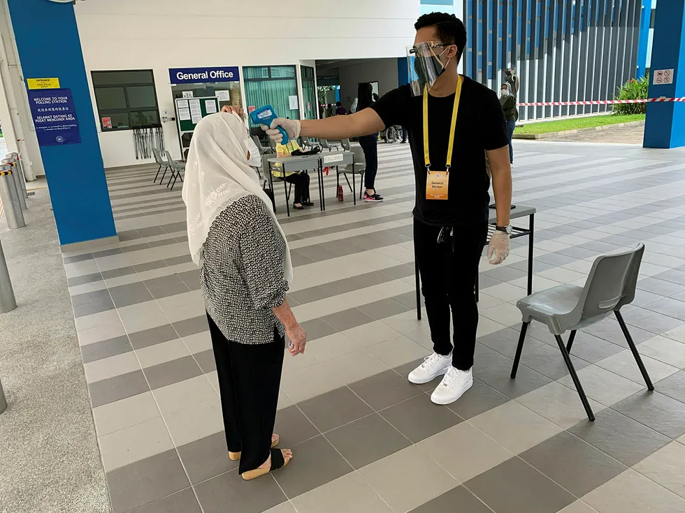 En velger i Singapore får temperaturen målt før hun kan avlegge stemme