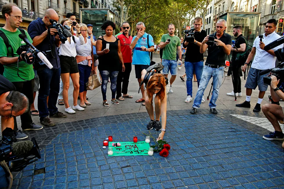 En kvinne plasserer blomster på et papir hvor det står «Catalunya – et sted for fred» på gaten La Rambla i Barcelona etter terrorangrepet. Foto: Manu Fernandez/AP/NTB Scanpix