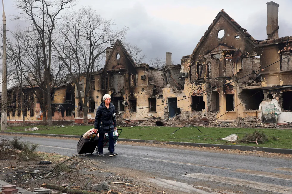 En kvinne går forbi ødelagte hus i den beleirede og istykkerbombede byen Mariupol, ved kysten lengst sør i Donbas-regionen i Ukraina. Bildet ble tatt i forrige uke i en del av byen som nå kontrolleres av prorussiske separatister.
