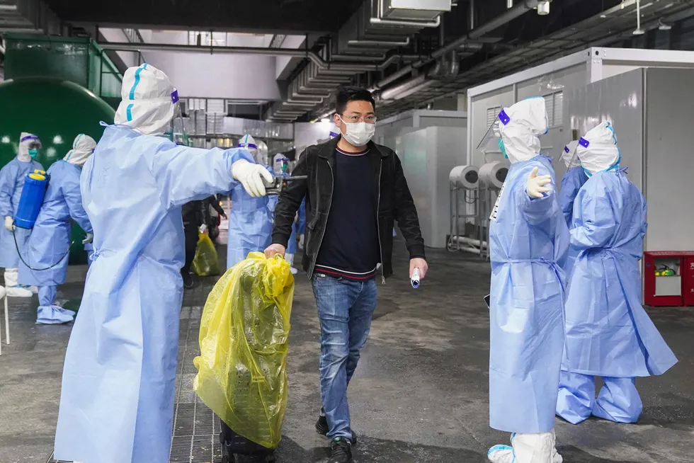 Helsearbeidere viser vei for pasienter som forlater et midlertidig covid-19-sykehus som er etablert i et kongressenter i Shanghai. Flere beboere i storbyen har klaget høylytt på den strenge nedstengingen av byen.