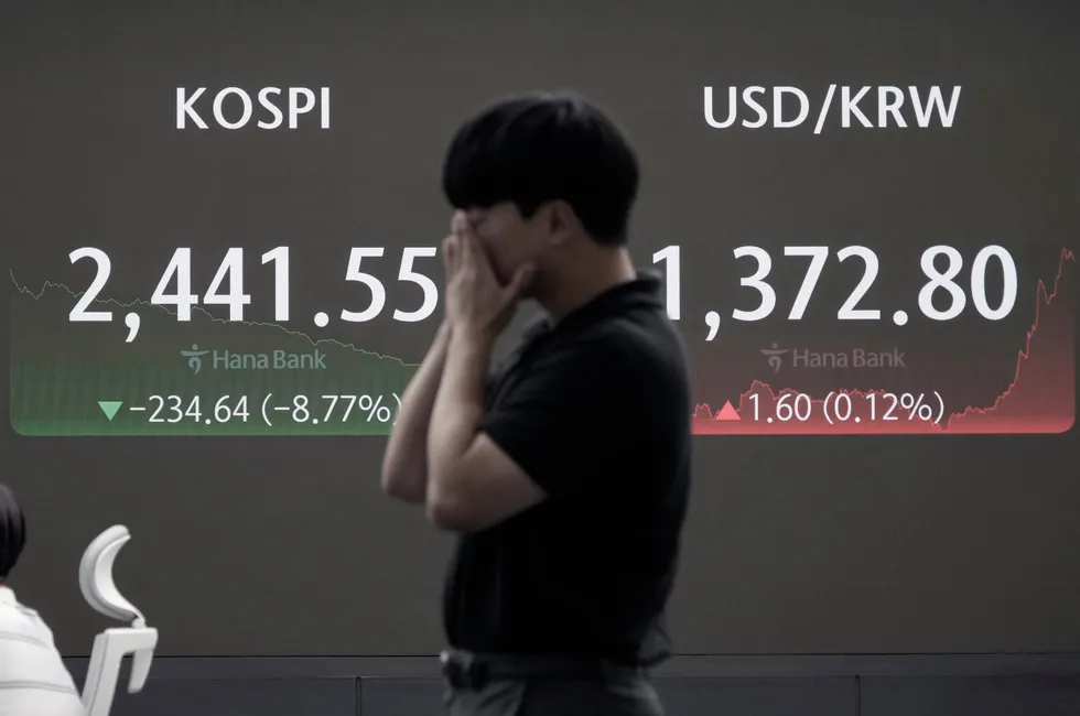 A currency trader reacts near a screen showing the Korea Composite Stock Price Index (left), and the foreign exchange rate between the US dollar and South Korean won at the foreign exchange dealing room of the KEB Hana Bank headquarters in Seoul, South Korea, on Monday.