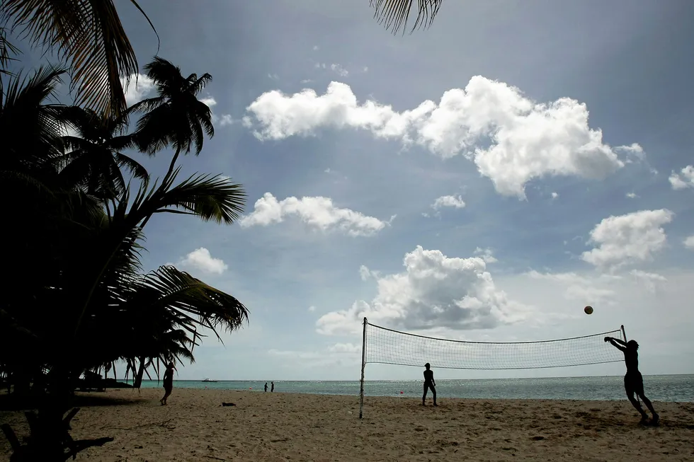 Tourist play volleyball on the beach at Pigeon Point, Tobago. Tobago, the smaller of the two main islands that make up the Republic of Trinidad and Tobago