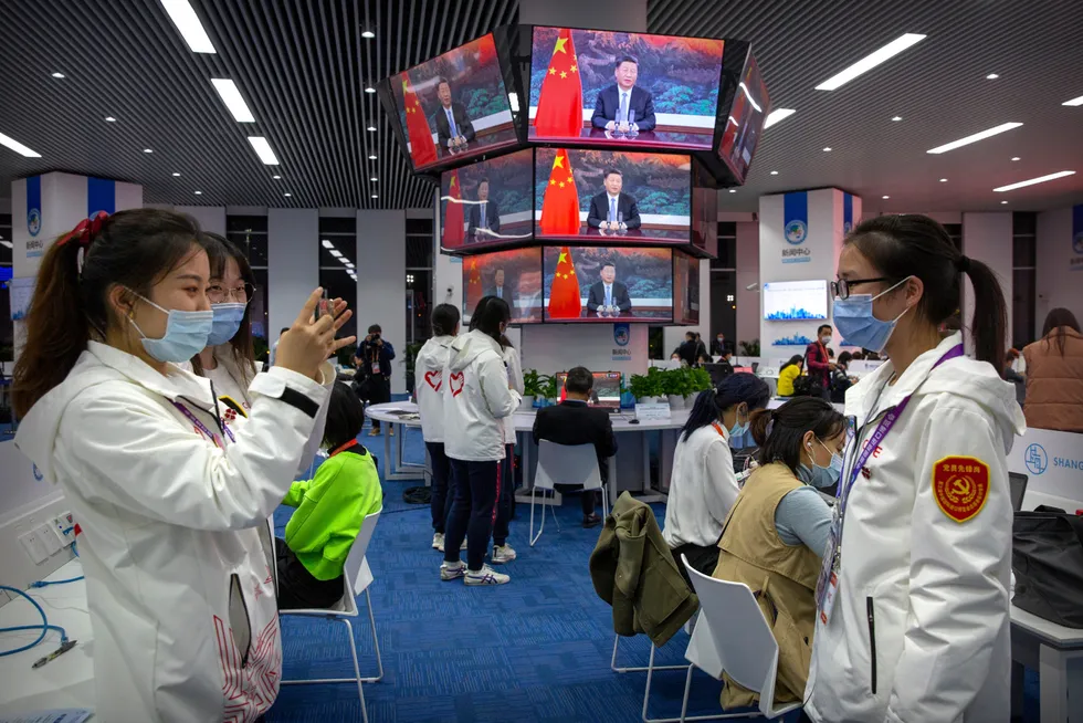 Frivillige tar bilder foran videoskjermene som viser president Xi Jinping åpne handelsmessen China International Import Expo i Shanghai i november.