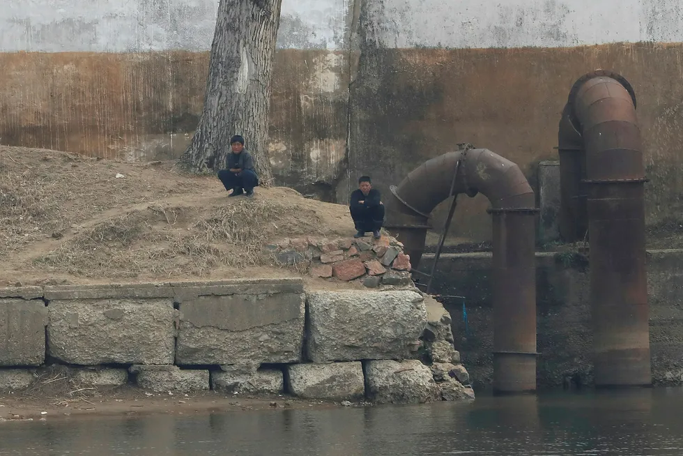 To nordkoreanere sitter på huk langs Yalu River i Sinuiju i Nord-Korea, som grenser mot byen Dandong i Kina. Foto: ALY SONG/Reuters/NTB Scanpix