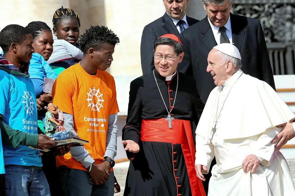 Campaign: Pope Francis (right) meets Cardinal Luis Antonio Tagle (second from right) and a group of migrants during an audience in St Peter's Square at the Vatican