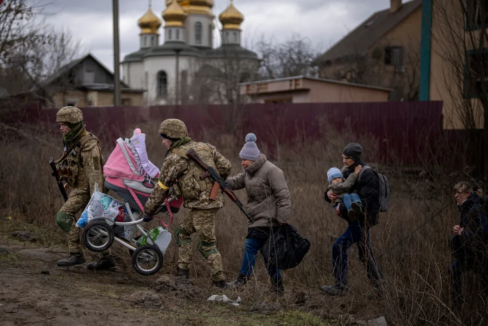 Midt i krisen sitter Norge og nyter godt av en finansiell blodoverføring av historiske dimensjoner grunnet økte energipriser, skriver innleggsforfatterne. Her fra utkanten av Kyiv, der ukrainske soldater hjelper en familie med å flykte.