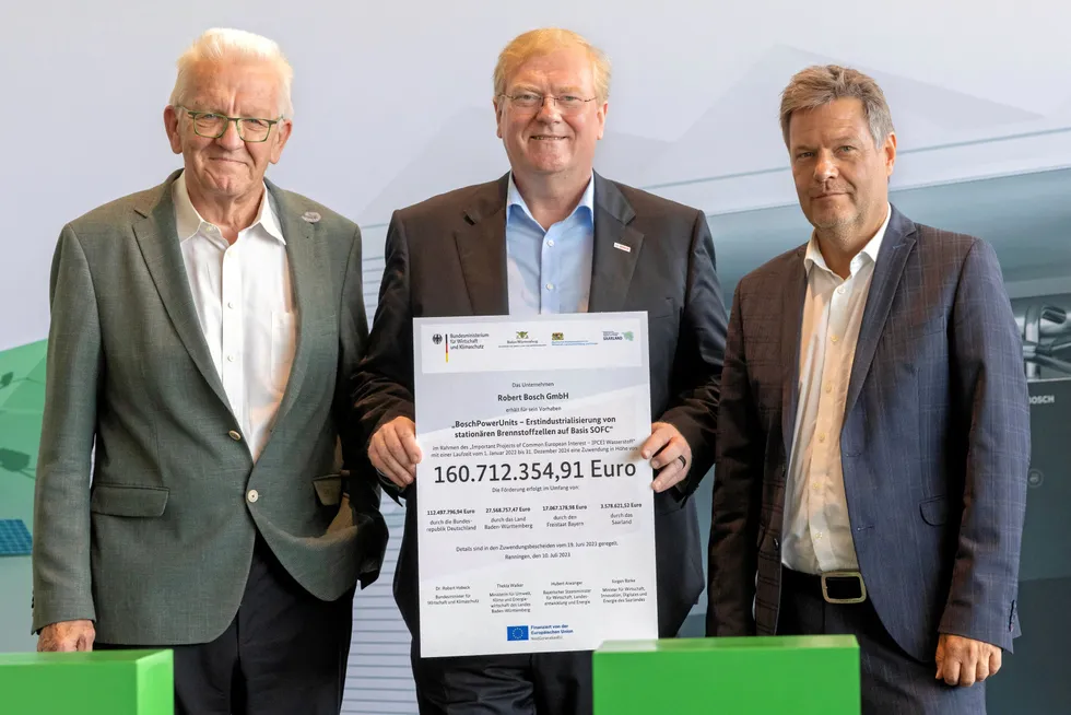 Bosch CEO Stefan Hartung, centre, is presented with the government grant by Vice-Chancellor Robert Habeck, right, in the presence of Baden-Württemberg minister-president Winfried Kretschmann, left.