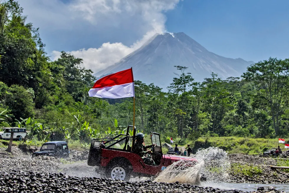 Red and white: an off-roader waves the Indonesian flag as he drives with Mount Merapi, one of the nation's most active volcanoes in the background