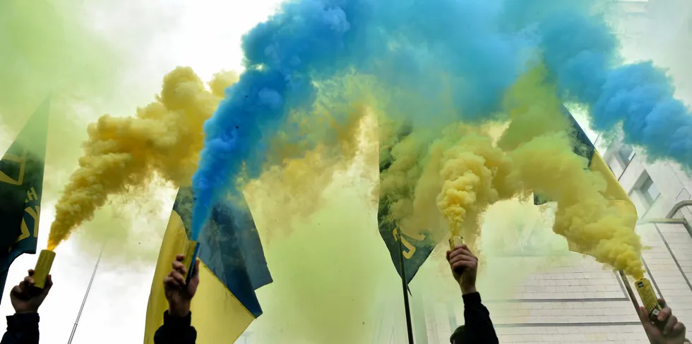 Demonstrators burn smoke bombs in the yellow-blue colours of the Ukrainian flag during a protest actiion