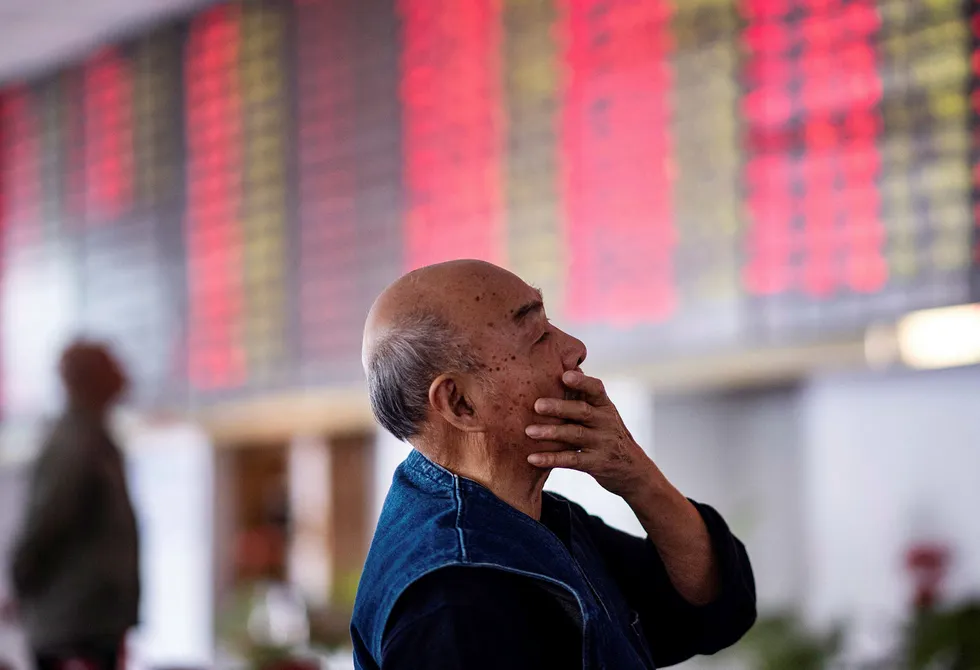En kinesisk investor ser opp på de elektroniske tavlene som viser børsutviklingen i et meglerhus i Shanghai tidligere i høst.