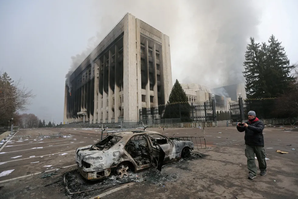 Unrest: a man takes a picture as a burned car is seen in front of the mayor's office building, which was torched during protests triggered by fuel price increase in Almaty, Kazakhstan