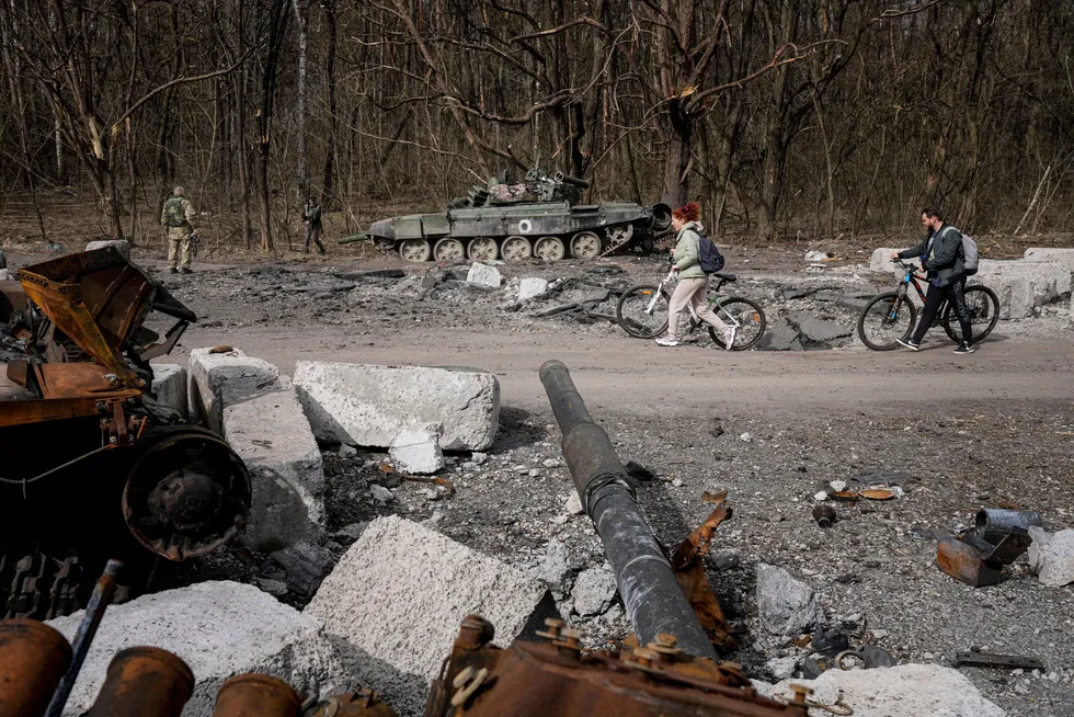Lokale innbyggere passere en ødelagt russisk stridsvogn i Tsjernihiv i Ukraina.