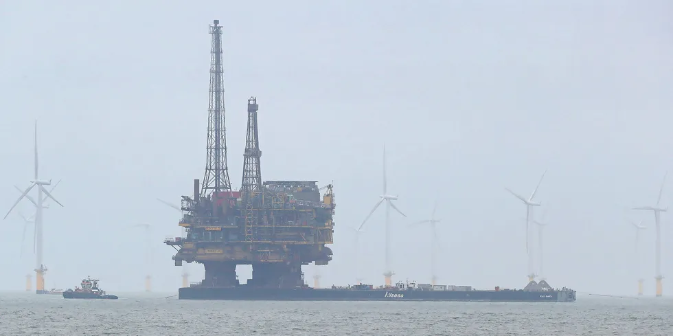 Shell's Brent Delta oil platform is towed past offshore wind turbines en route to Able Seaton Port for decommissioning