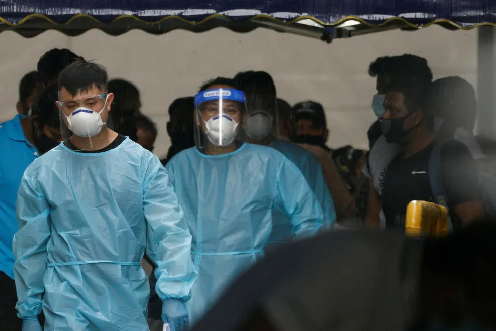 Earlier outbreak: personnel in protective gear usher a group of Covid-positive migrant workers to a bus to a Singapore government quarantine facility