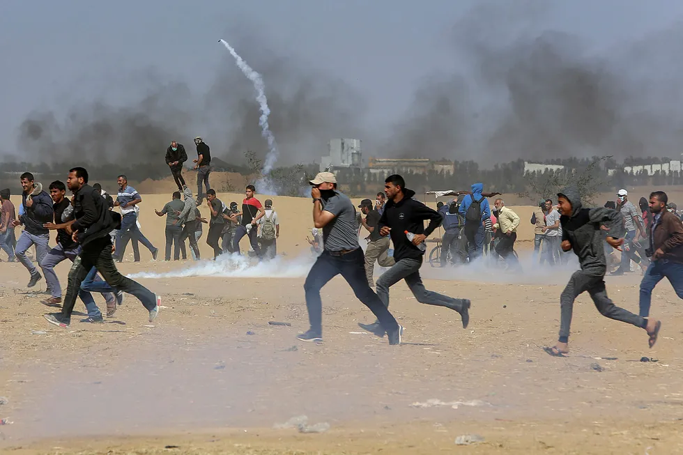 Palestinske demonstranter løper bort fra tåregass som israelske soldater har skutt mot dem på Gazastripen tirsdag. Foto: AP / NTB scanpix