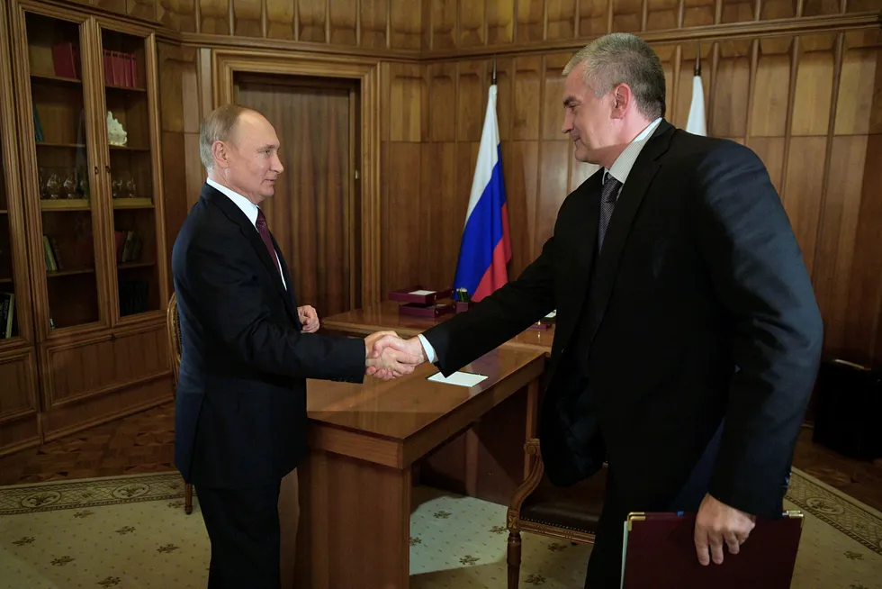 Russlands president Vladimir Putin utfører sine plikter som før. Her håndhilser han på regjeringssjefen for Krim, Sergei Aksyonov, under et møte på Krim forrige torsdag.