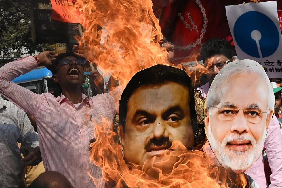 En representant for Indias Congress Party ropte slagord og brente bilder av statsminister Narendra Modi og næringslivstoppen Gautam Adani i protest mot regjeringens økonomiske politikk i Kolkata på mandag.
