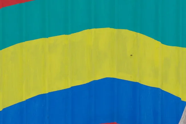 A Gabonese flag painted on a fence surrounding a construction site.