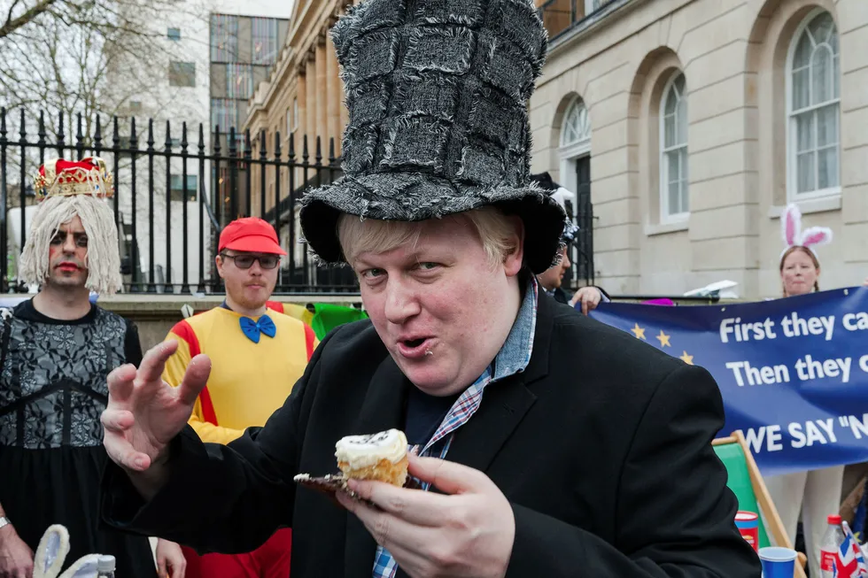 Boris Johnson-imitator, Drew Miles, gjør som mannen han prøver å etterligne: «I'm pro having my cake and pro eating it». Dette skjedde ved Brexit Wonderland tea party, en Alice i Underland-inspirert protest i London for nesten et år siden. Foto: Barcroft Media/Getty Images