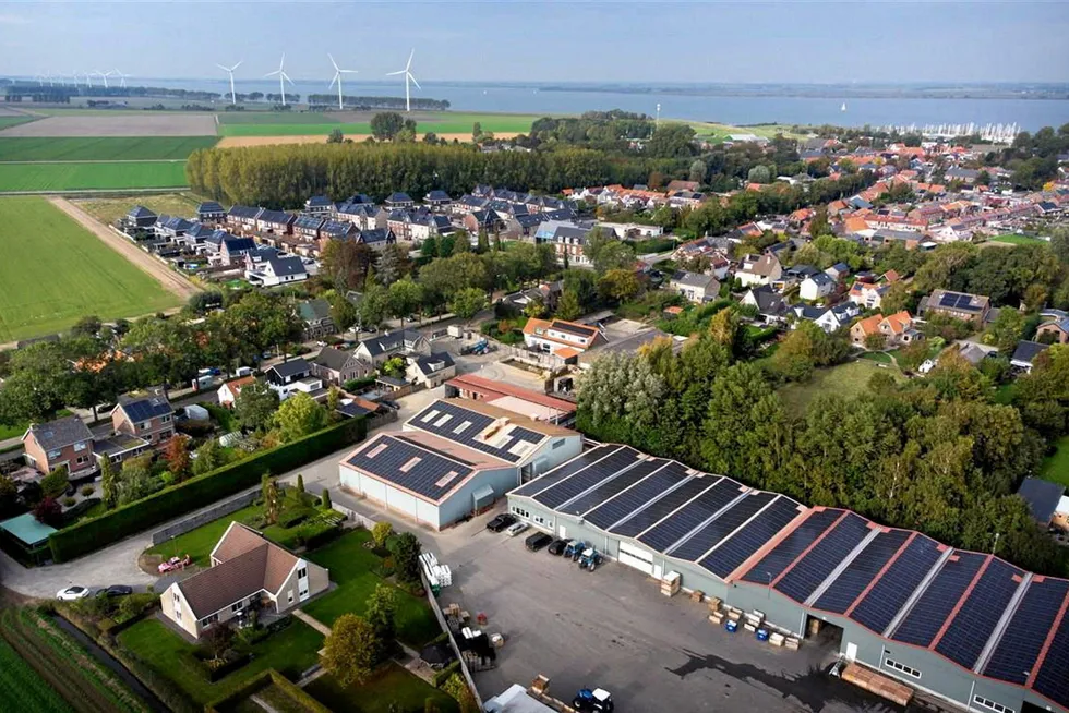 An aerial view of Stad aan 't Haringvliet, which means City on the Herring Flow, showing local wind turbines and solar panels.