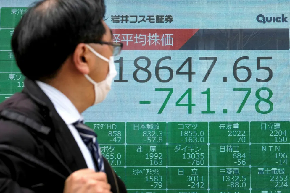 Watching the markets: a man wearing a fast mask walks past a quotation board displaying share prices of the Tokyo Stock Exchange