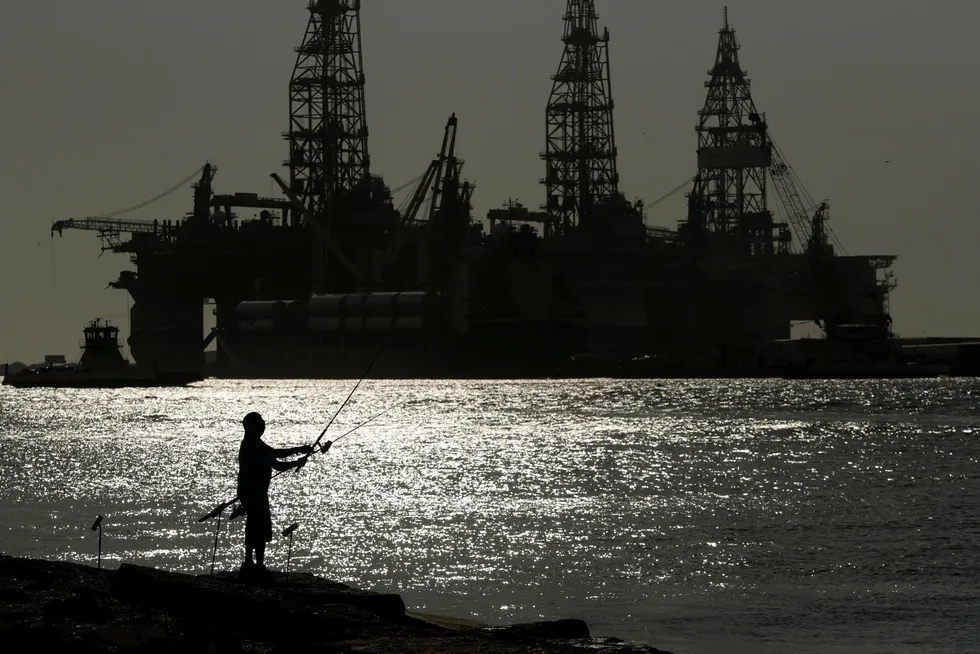 Hunting for finance: Can explorers provide enough bait to secure funds to drill? A man fishes near drilling rigs at Port Aransas, Texas three years ago.