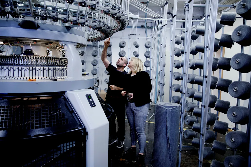Styreleder og hovedeier av Janusfabrikken, Janne Vangen Solheim, ser på en av bedriftens nye maskiner sammen med produksjonsarbeider Khaled Almamo.