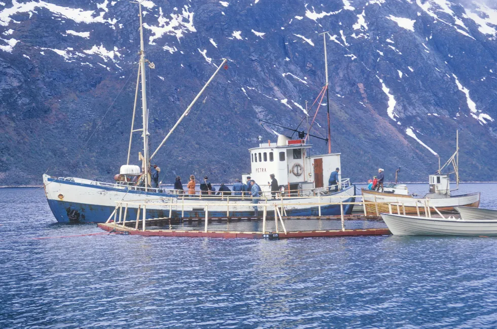 Brønnbåten «Petra» losser smolt hos Flakstad fiskeoppdrett A/S i Indre Selfjord, Senja. Anlegget tilhørte Torbjørn Flakstad fra Flakstadvåg på Senja. «Petra» hadde hjemmehavn på Smøla, og eier og skipper var Steinar Arnøy. Bildet er tatt i 1974.