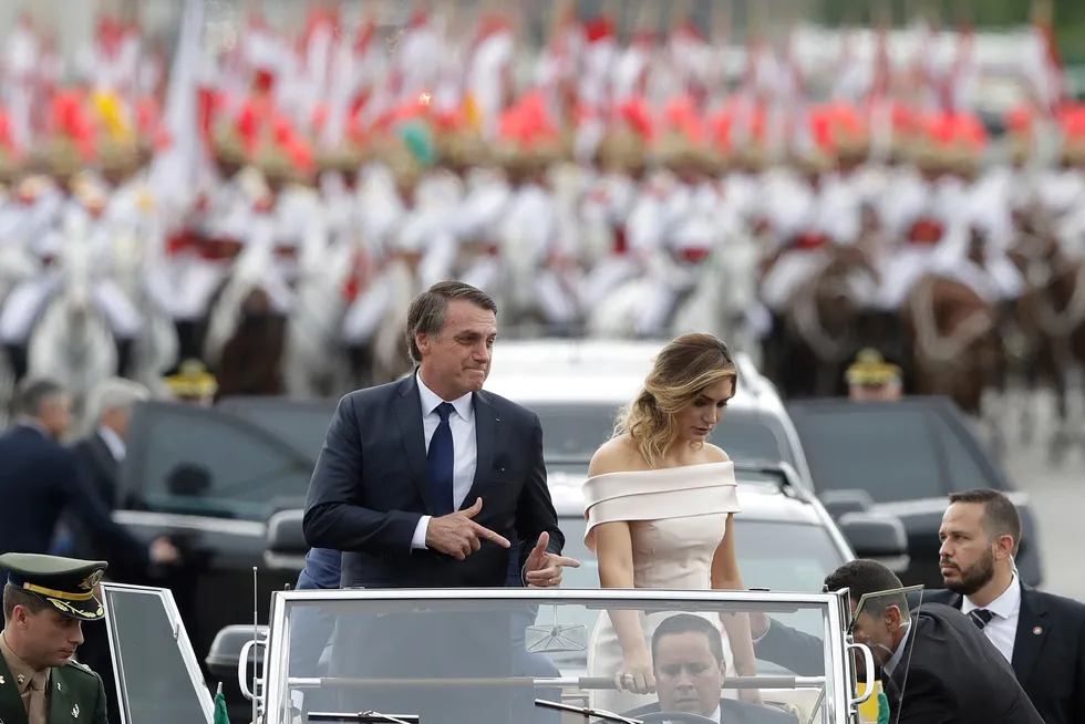 Aiming: Brazilian President Jair Bolsonaro points with his fingers to mimic guns (his trademark) as he rides in an open car with his wife, first lady Michelle Bolsonaro