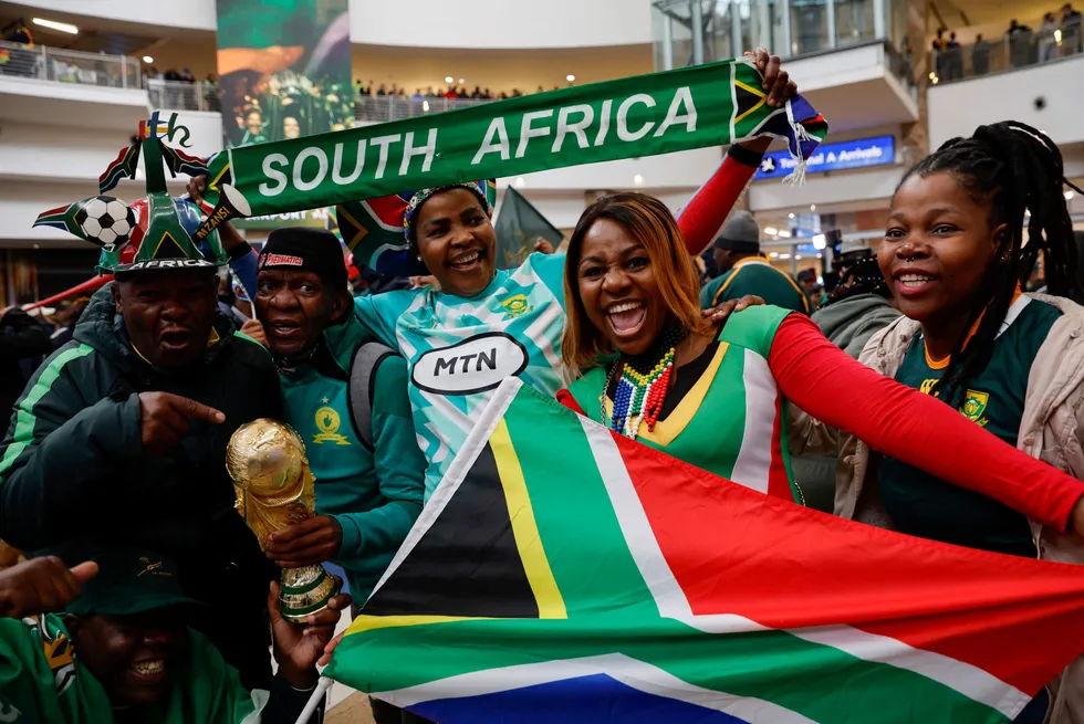 Anticipation: Excited supporters holding a South African flag and a trophy react await the arrival of the nation’s word cup wining rugby team in Johannesburg last month.