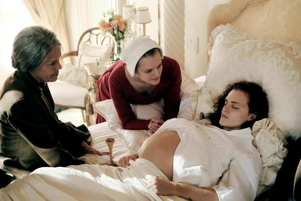 Offred (Elisabeth Moss i midten) hjelper til under fødselen til en annen tjenerinne, Janine (Madeline Brewer) i HBO-serien «Tjenerinnens beretning». Foto: George Kraychyk/HBO