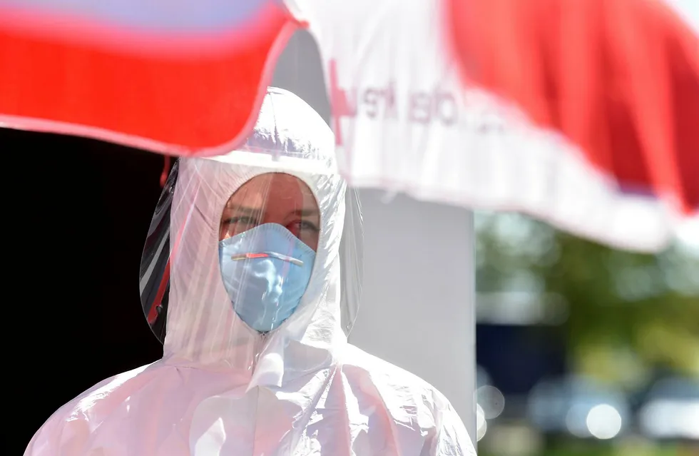 A health worker wears protective clotes while taking samples of persons arriving in their cars at a new coronavirus Covid-19 testing station for travelers from the motorway at the motorway service area Hochfelln near Ruhpolding, southern Germany