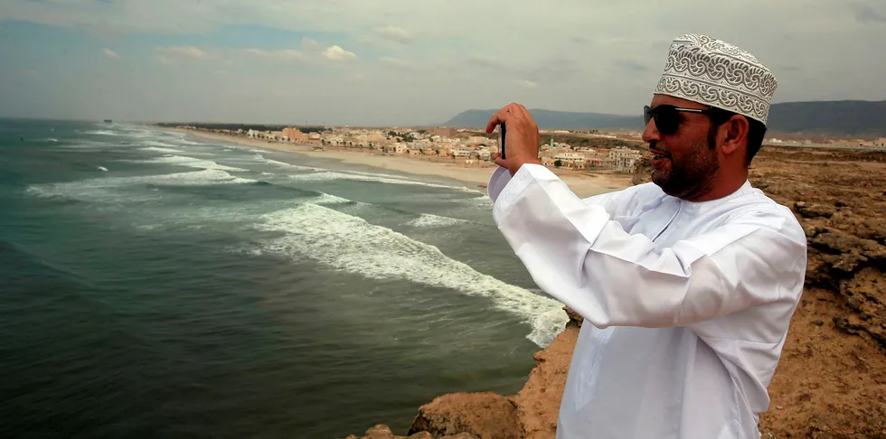 An Omani man takes a photo as waves crash on the shore of the southern Omani city of Salalah.