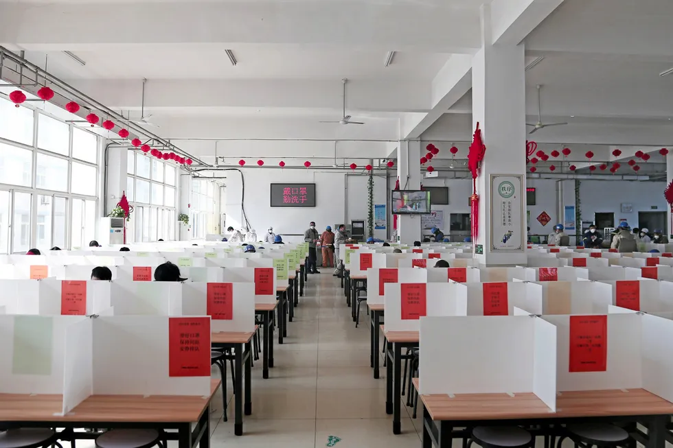 Partitioned dining tables at the CIMC Raffles canteen, which the Chinese yard introduced to help prevent workers from contracting coronavirus. Printed on the red paper signs is the precautionary advice: no chatting, no gathering, eat fast and leave soon.