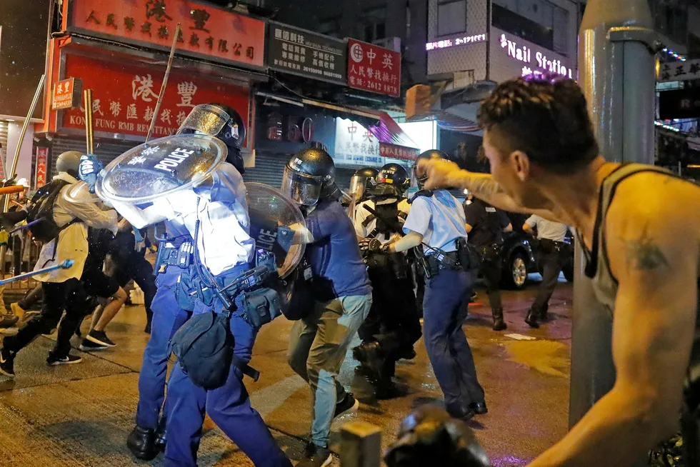 En mann kaster en stein på opprørspolitiet i Hongkong.