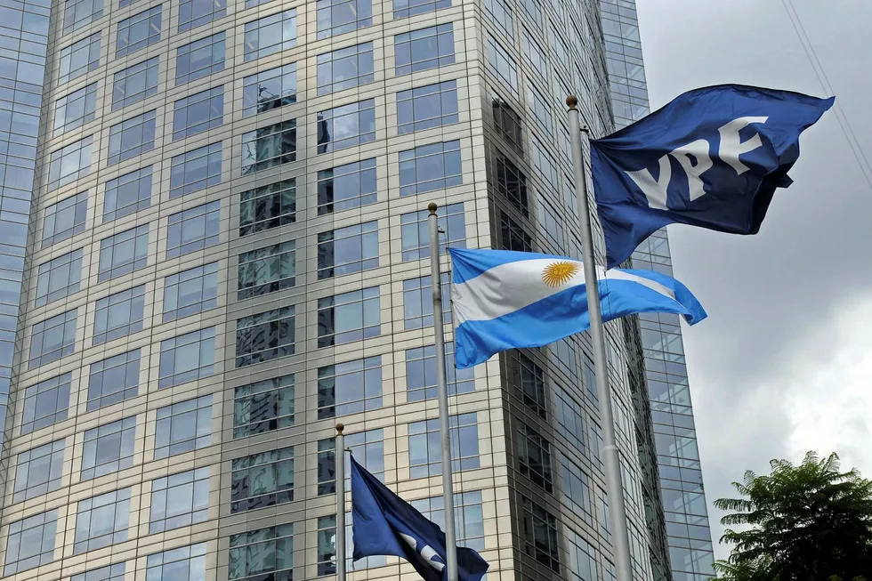 Flags of Argentine oil company YPF flutter next to an Argentinian national flag outside Repsol-YPF headquarters in Buenos Aires on April 11, 2012. AFP PHOTO / NA - JUAN VARGAS