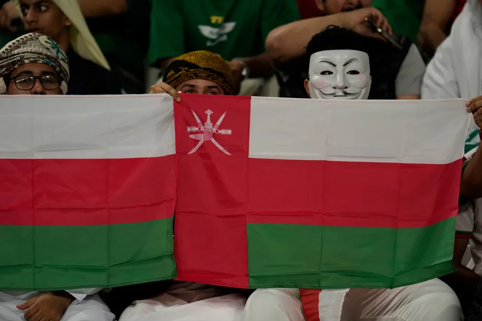 Supporters of Oman holding the nation's flag ahead of a soccer match.